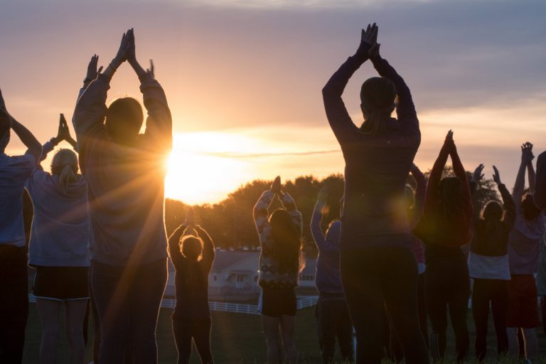 students participating in sunset yoga outside on horsebarn hill
