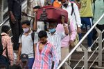 Migrant workers from other states arrive at the Anand Vihar bus terminal, in New Delhi on August 18, 2020. - India's official coronavirus death soared past 50,000 on August 17 as the pandemic rages through smaller cities and rural areas where health care is feeble and stigmatisation rife.