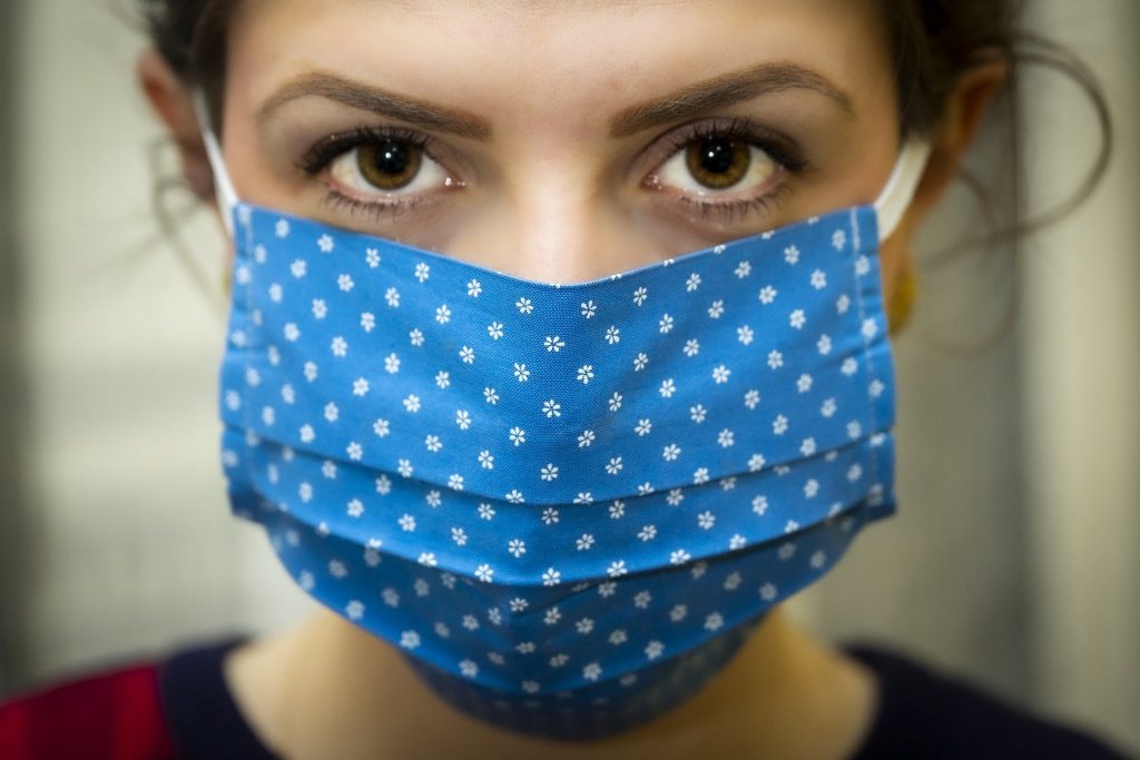 woman looking at the camera wearing a blue mask with white polka dots