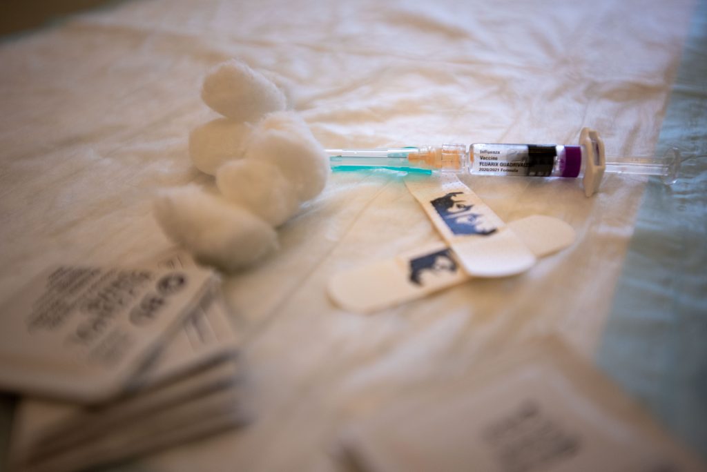 An influenza vaccine needle next to band-aids and cotton balls.