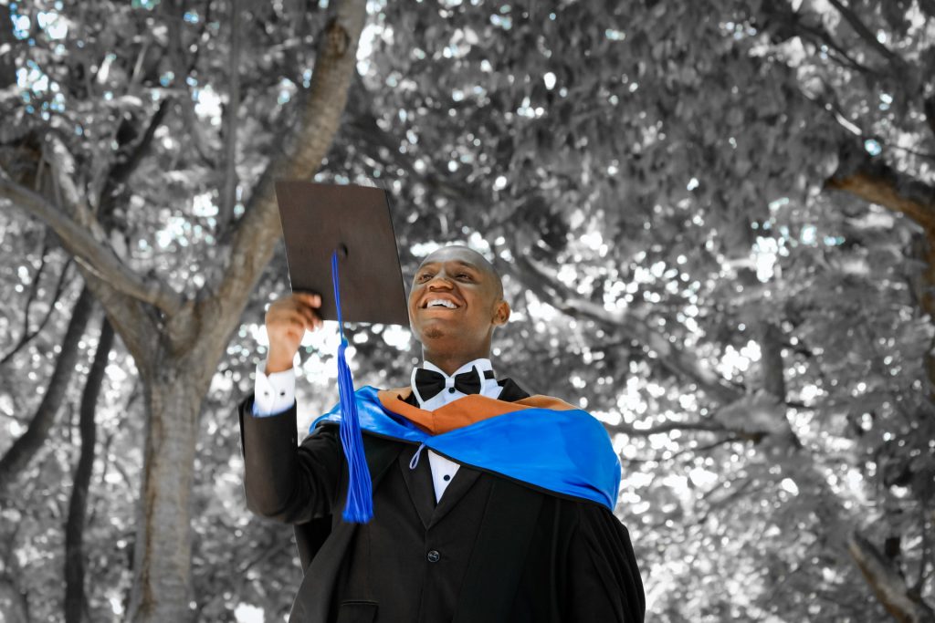 Black teenager smiling in cap and gown