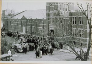 A photo from 1940 of Hawley Armory, showing the front of the building crowded with people and cars on the day of a UConn basketball game.