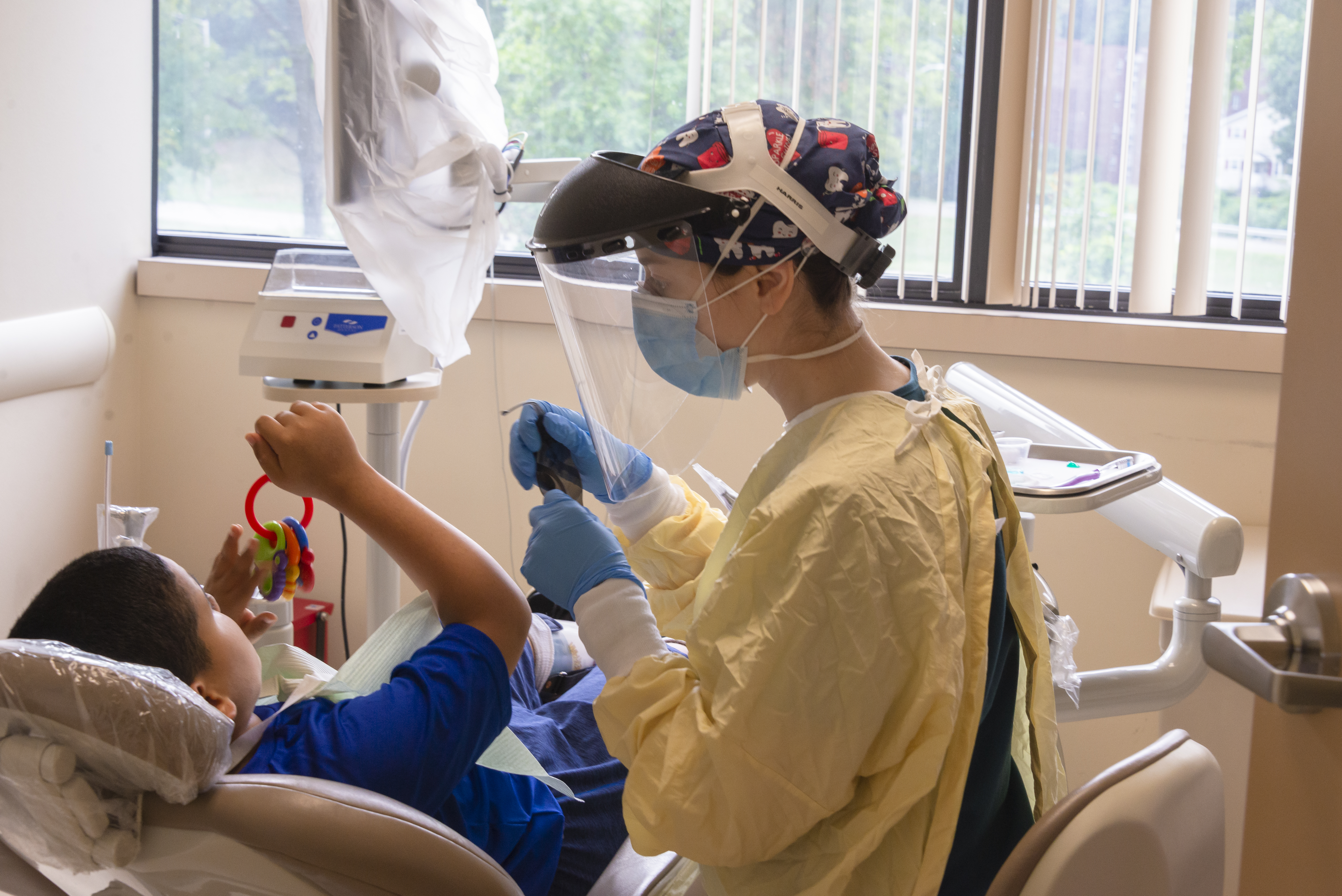 A dental resident in PPE assists a young patient at the UConn School of Dental Medicine clinic in West Hartford.