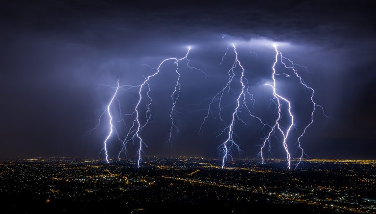 Lightning strikes over a city at night, illustrating the sudden and dangerous nature of so-called cytokine storms, potentially fatal episodes where inflammation-causing proteins flood the blood.