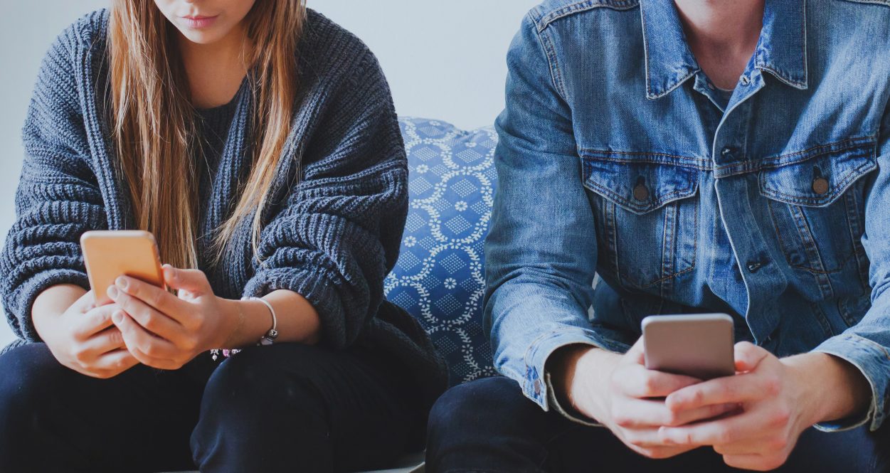 internet and social network addiction, man and woman holding smartphones while sitting together, problem of virtual communication