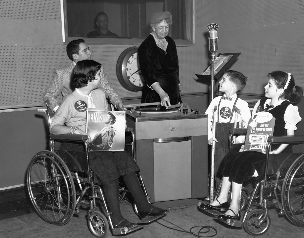 Eleanor Roosevelt acts as a disk jockey for children afflicted with polio. The purpose of the broadcast was to generate interest in a series of talent shows nationwide benefiting the March of Dimes. The children in the studio with Mrs. Roosevelt are (left to right): Florence Krieger, 15; Allen Fox, 13; George Redmond, 9; and Joyce Alexander, 12.