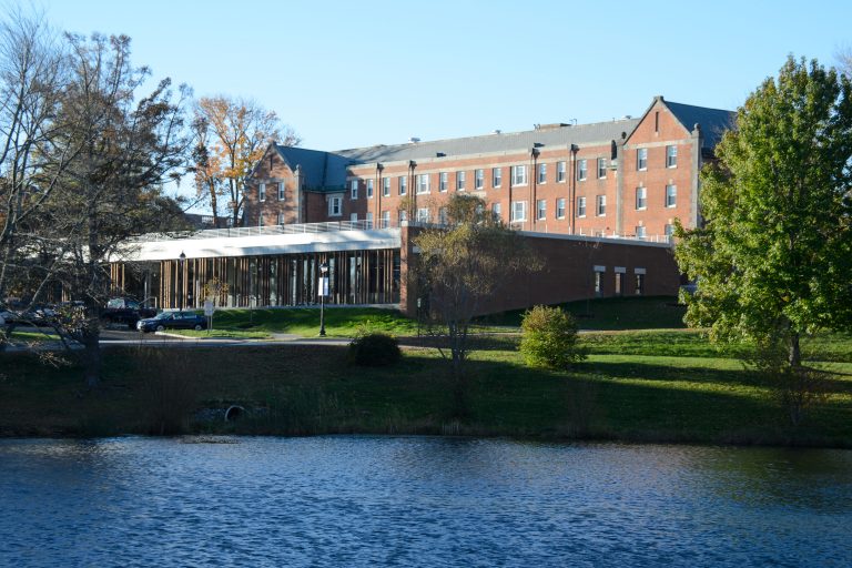 Storrs Hall is seen from the opposite side of Swan Lake.