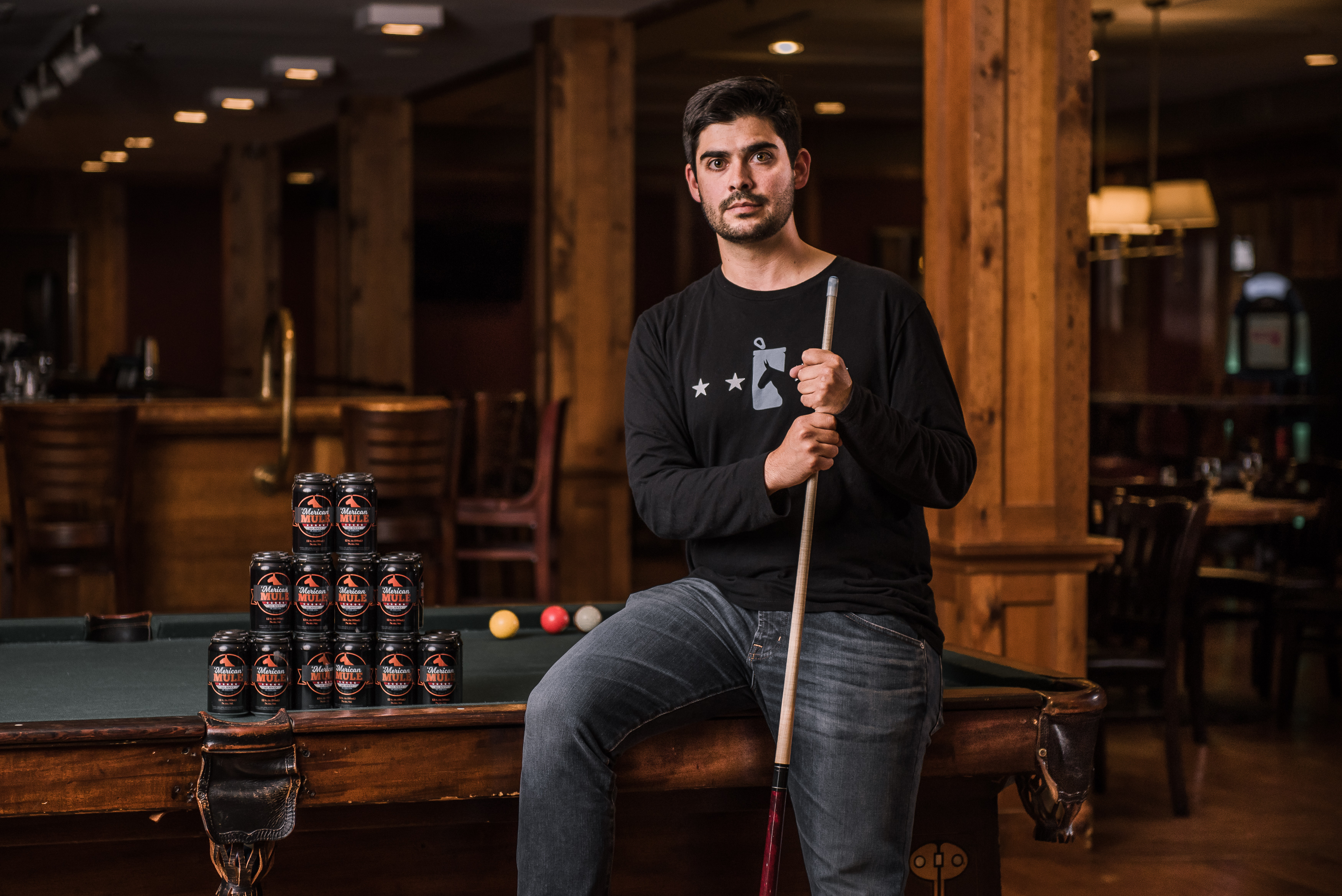 UConn graduate Dean Mahoney, founder of the 'Merican Mule cocktail company, posing with a pool cue.