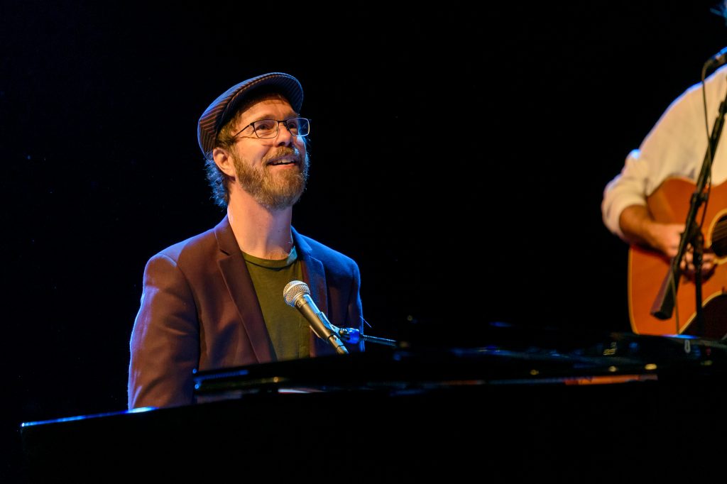Ben Folds, who will play virtually at UConn on March 4, seated behind a piano during a concert.