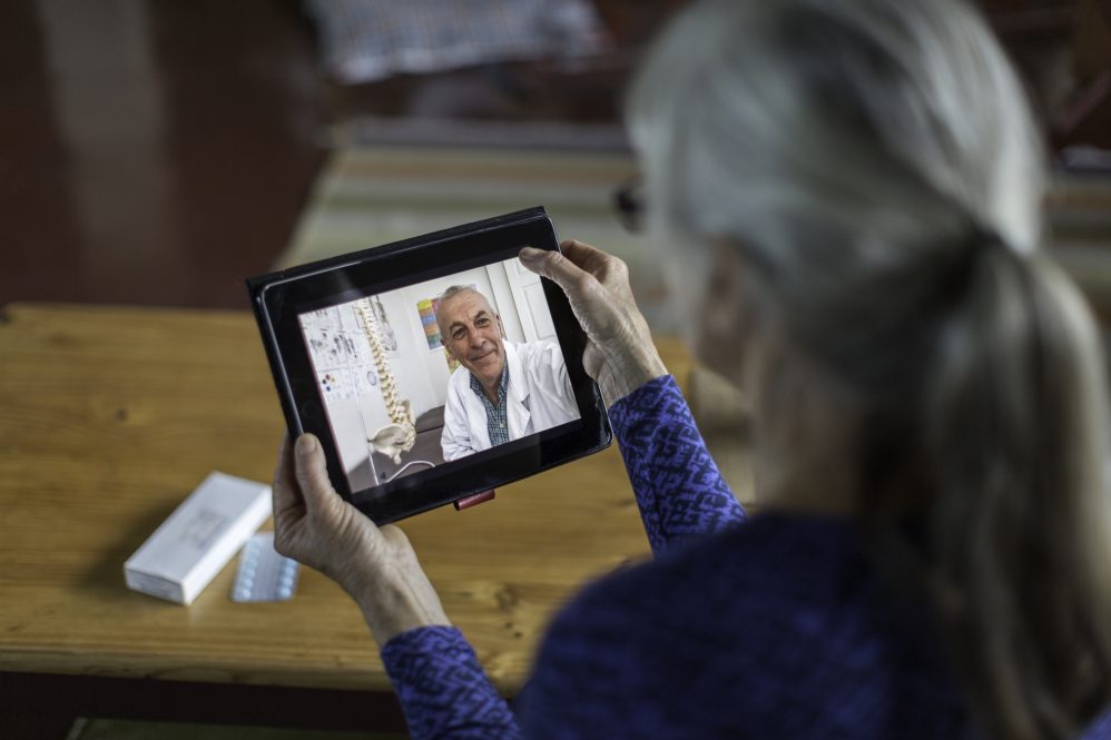An older woman talks with her doctor via computer tablet, illustrating the type of telemedicine being discussed by the research study in the story.