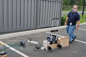 Dean Moroniti with computer and telephone components in a parking lot