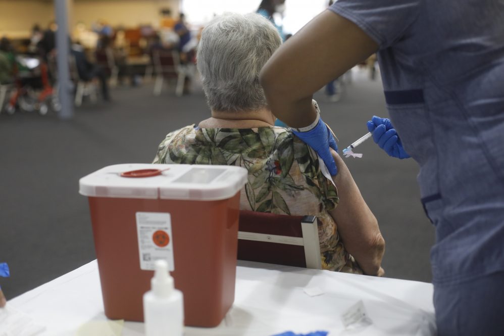An older woman seen from behind as she receives the COVID-19 vaccine at an outdoor vaccination center. UConn Health researchers are studying why COVID-19 is so much deadlier for older adults, in a project that will yield insights into the effect of vaccines on adult immune systems.