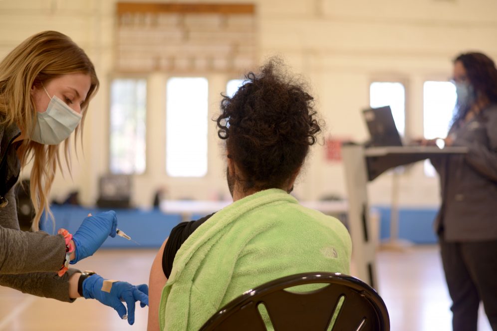On left, UConn Health Registered Nurse, Savannah Jaspering administers the COVID-19 vaccine while at the Hawley Armory in Storrs last spring