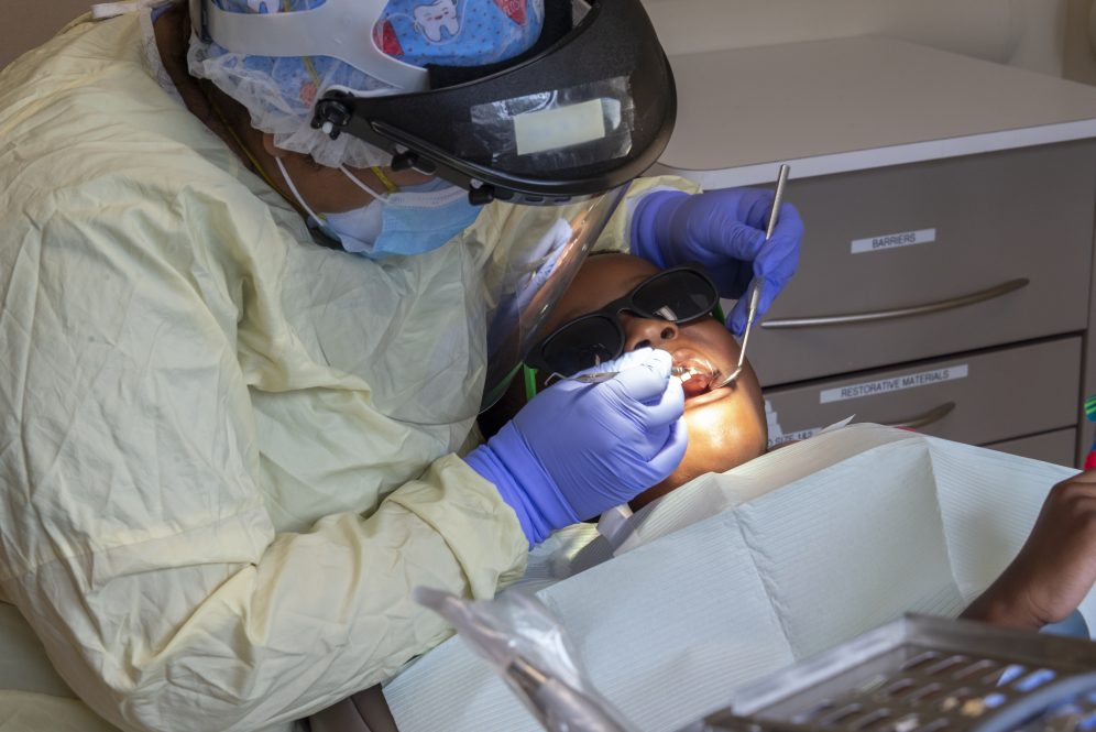 A dental resident examining a young patient. Despite a high risk of COVID-19 transmission, infection rates among dentists are actually lower than among other front-line health professionals.