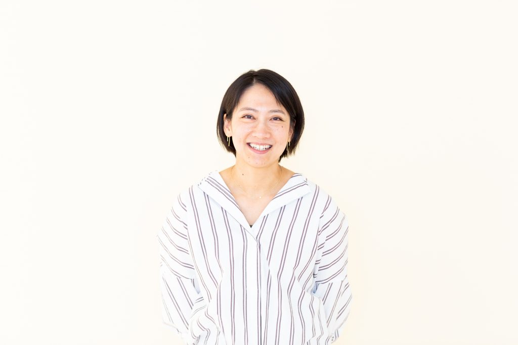 Smiling Asian woman stands in front of white background