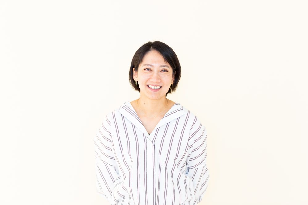Smiling Asian woman stands in front of white background