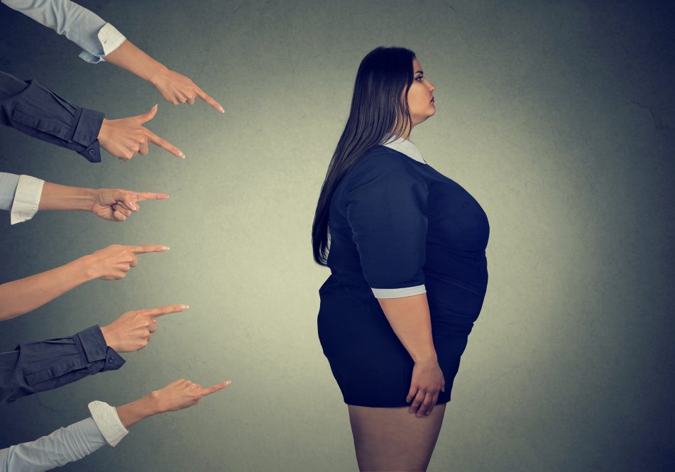 An illustration of hands pointing at a woman who is overweight. A new study examines the experience of weight stigma across six different countries.