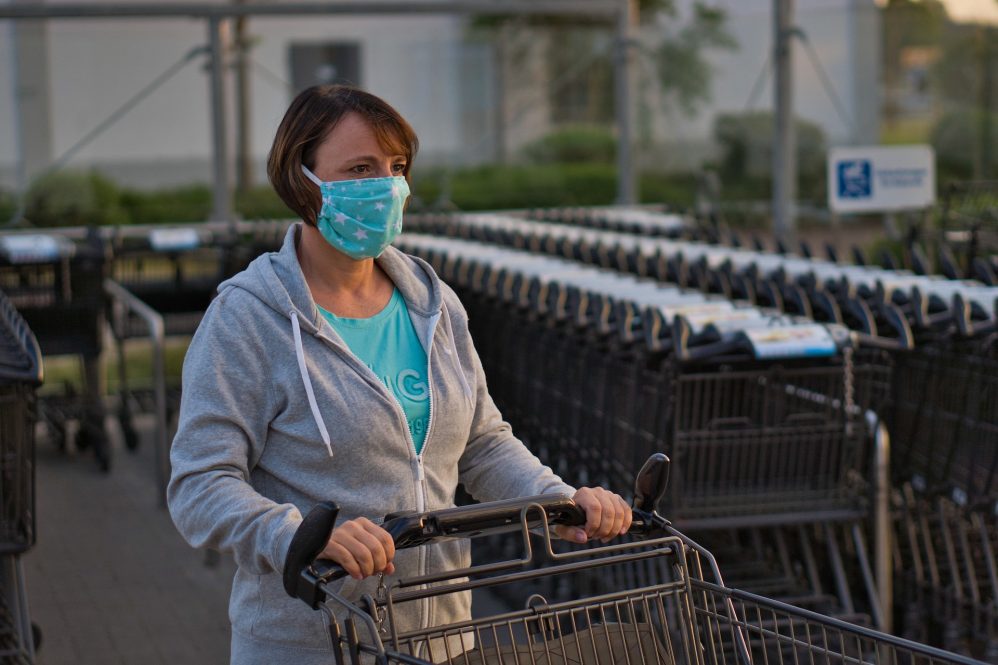 White middle-aged woman in a mask with a grocery cart