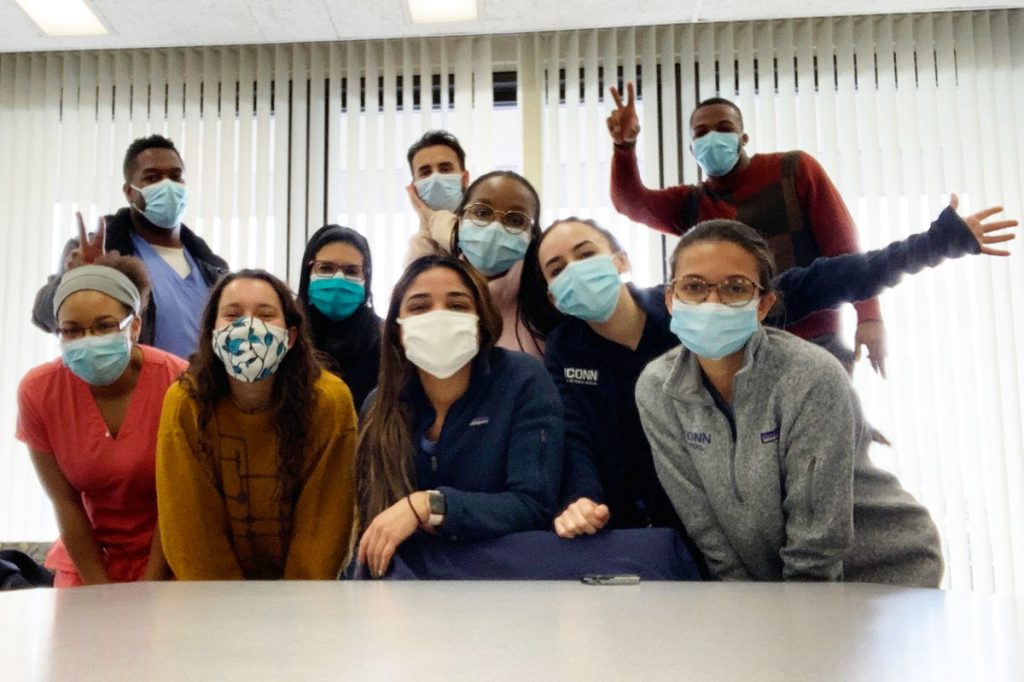Group shot of dental students in masks behind a conference table