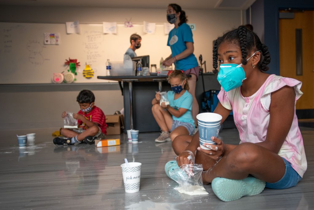 A student at BRAIN Camp, mixes corn starch and water to make oobleck during a camp activity.