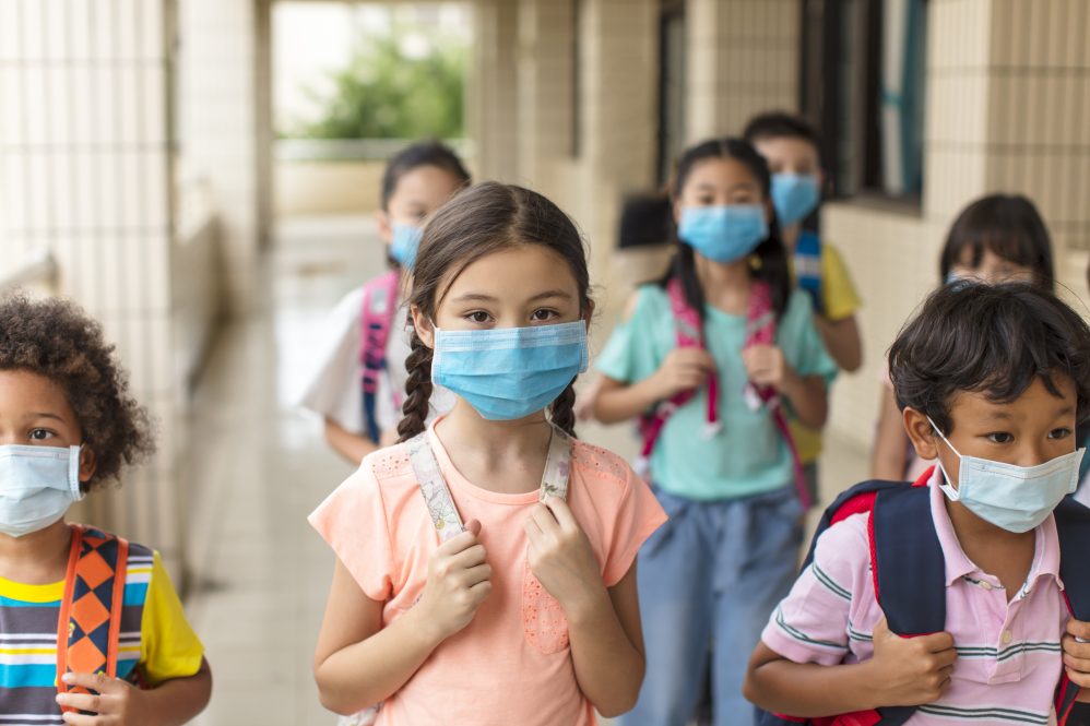 Elementary school children returning to class after summer break, wearing facemasks.