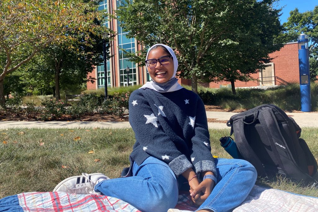 Smiling female student sitting in the grass