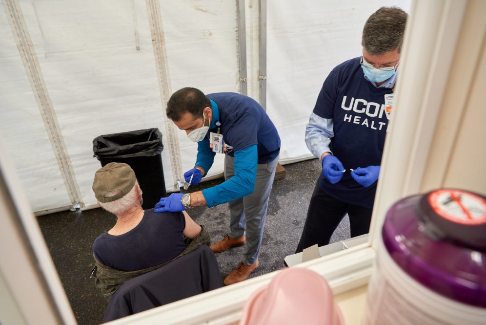 Steven Angus MD, assistant dean of graduate medical education, and Angad Deengar, a pulmonary and critical care fellow, administer COVID-19 vaccine at the UConn Health FEMA mobile vaccination unit at St. Mary's Church in Norwich on May 5, 2021.