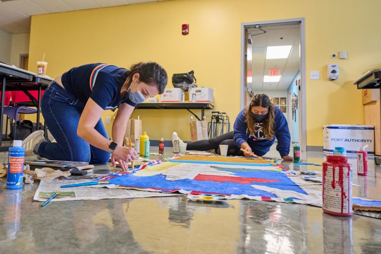 Brunna Louzada '22 (SFA), left, and Kate Gavilanes '22 (CLAS) paint a banner for the the homecoming parade at the Puerto Rican / Latin American Cultural Center on Oct. 1, 2021.