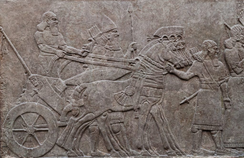 Relief of ancient assyrian warriors in a horse drawn chariot.
