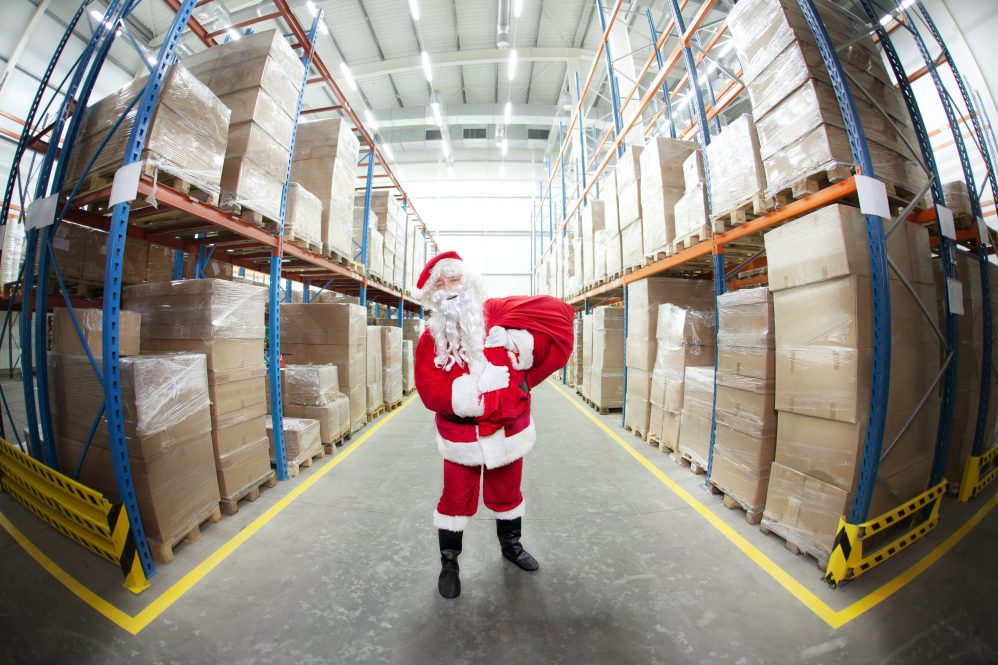 A person dressed as Santa Claus, standing in a warehouse. Pandemic-related supply chain issues have caused a shortage of popular consumer goods ahead of the 2021 holiday season.