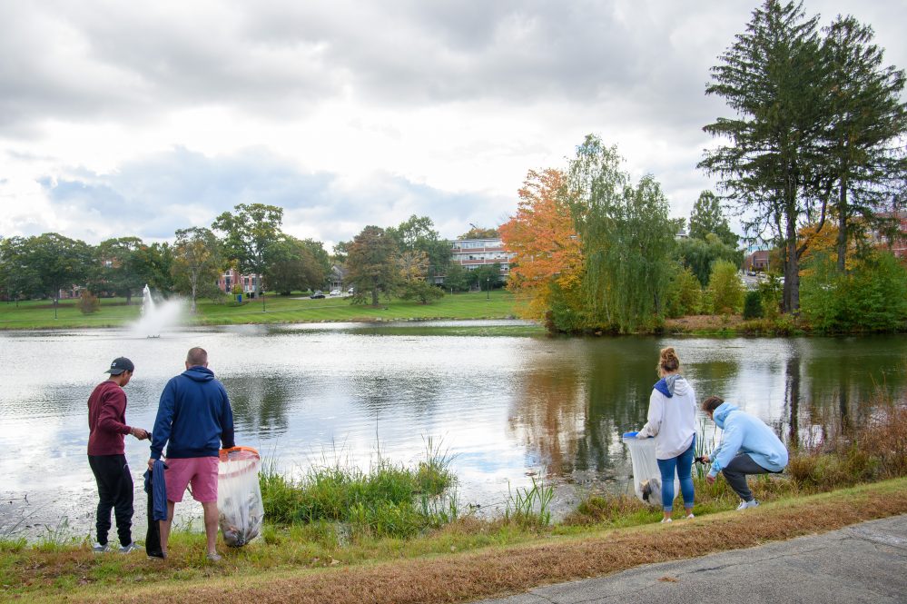 Jon Contaxis '25 (PHARM) left, his father Bill Contaxis '90 (ENG) of Milford, Rebecca Leelman '24 (ENG) and Nikita Karasik of Salem Mass. pick up trash around Mirror Lake on Oct. 17, 2021.