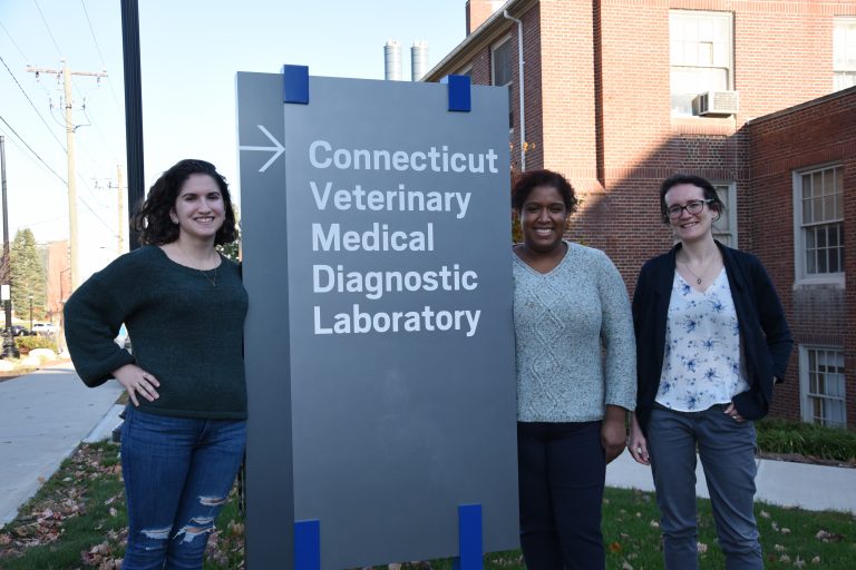 Three women standing in front of CVMDL sign on UConn campus