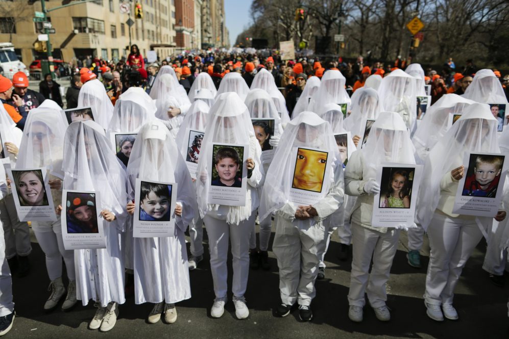 People display portraits of Sandy Hook elementary school shooting victims as they take part in the March for Our Lives in New York on March 24, 2018.