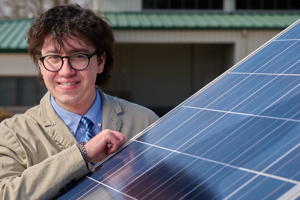 Liam Enea '24 (CAHNR), founder and president of the Clean Energy Society stands next to solar panels at the Depot campus on Feb. 16, 2022. (Peter Morenus/UConn Photo)