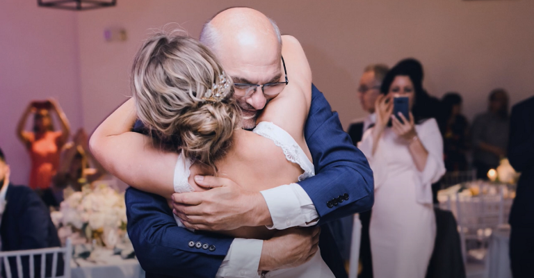 A father and daughter embrace after dancing at her wedding.
