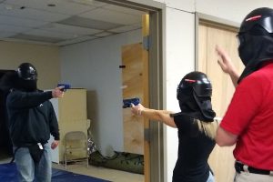 Participants in a use of force demonstration point simulated firearms at each other