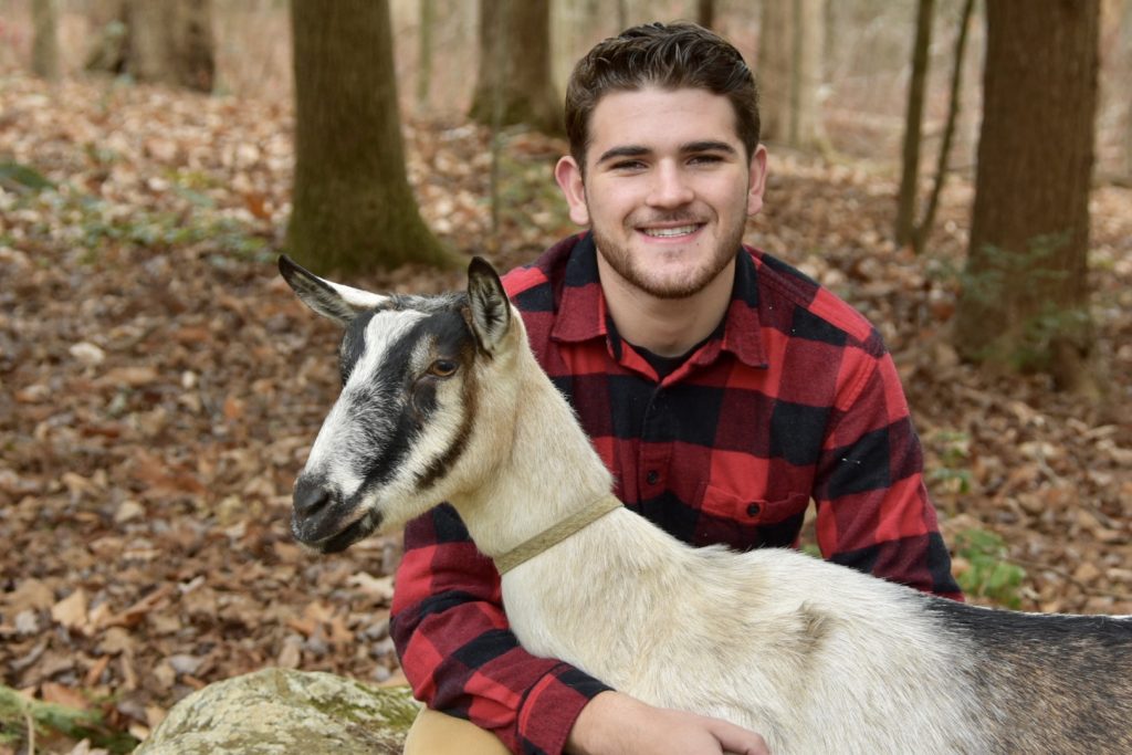 Smiling male student with a goat