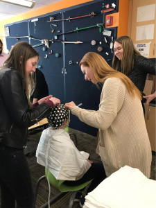 Researchers from Dr. Landi’s lab training high school student interns to place an EEG cap on a younger student’s head at the AIM Academy. (Landi Lab Photo, with permission from AIM Academy).
