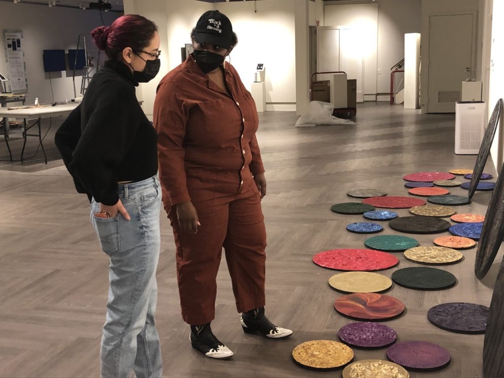 Kaelynne Hernandez '22 (SFA), left, and Ashante Kindle '22 MFA talk about Kindle's art installation at the William Benton Museum of Art recently. The 2022 Studio Art and Digital Media and Design Master of Fine Arts Thesis Exhibition will be on display through May 8. (Kimberly Phillips/UConn Today)