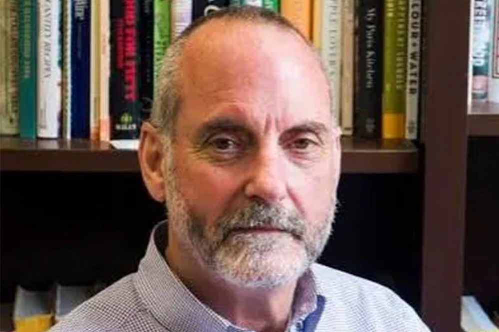 A portrait of a man in front of a bookshelf