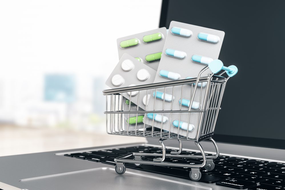 Business pharmacy online with pills in shopping cart on laptop on abstract background.
