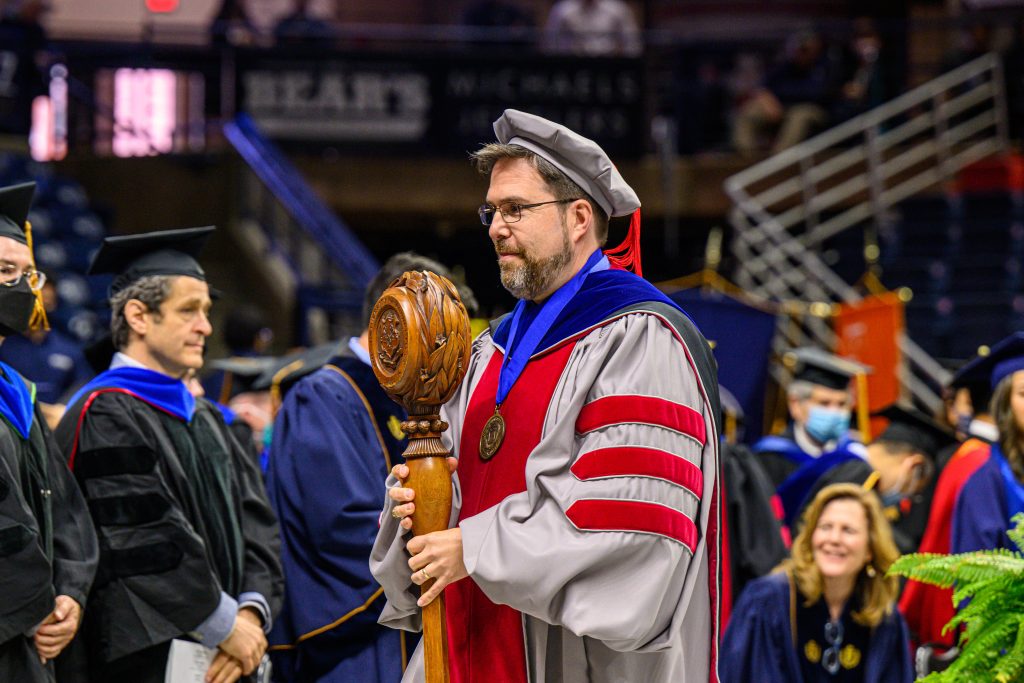 Daniel Burkey, school marshal, carries the mace during the recessional of the School of Engineering Commencement ceremony at Gampel Pavilion