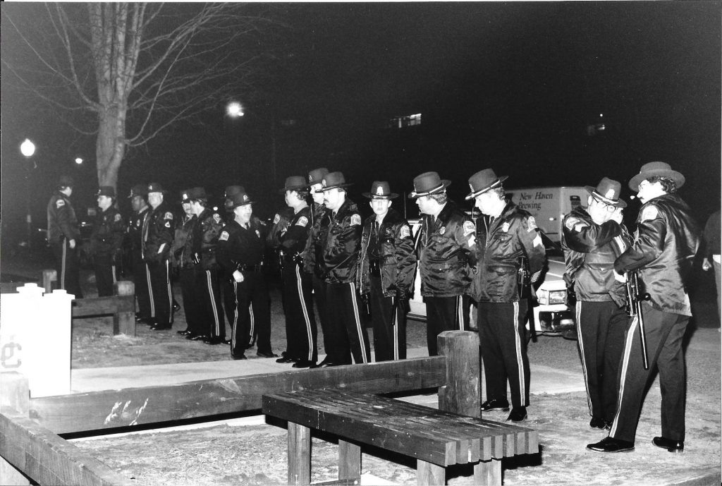 A black and white photo from the 1980s of UConn police officers standing in a line outside at night.