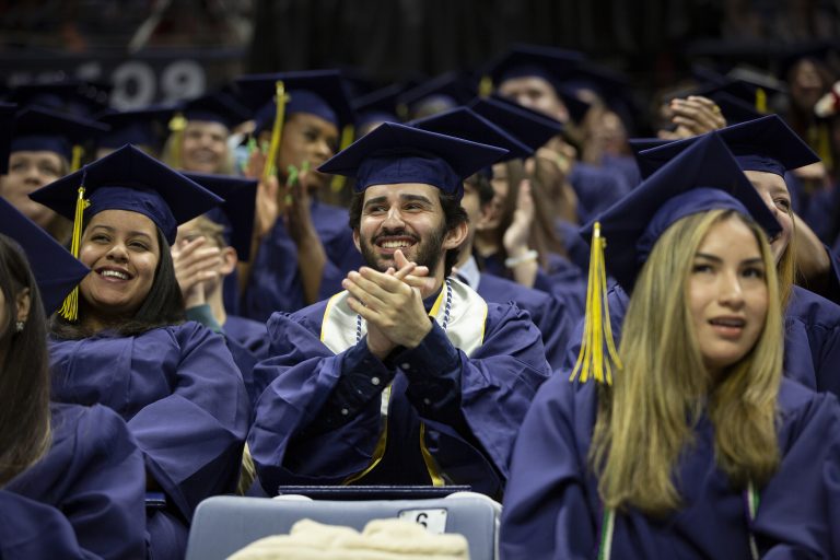 Graduate claps during commencement ceremony