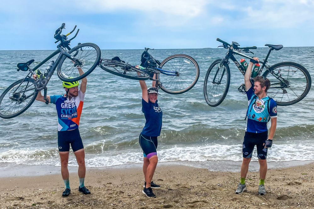 Cyclists hold up their bikes on the Atlantic shore