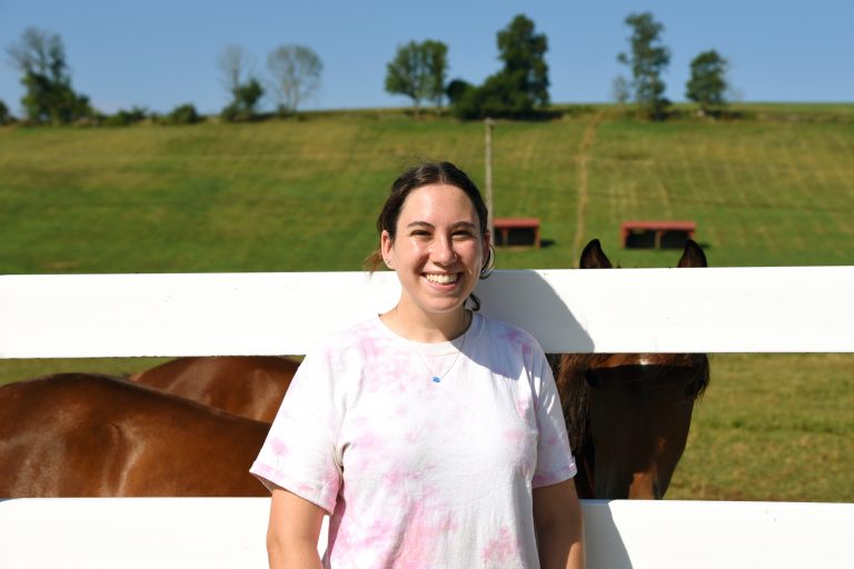 Smiling female student in front of horses