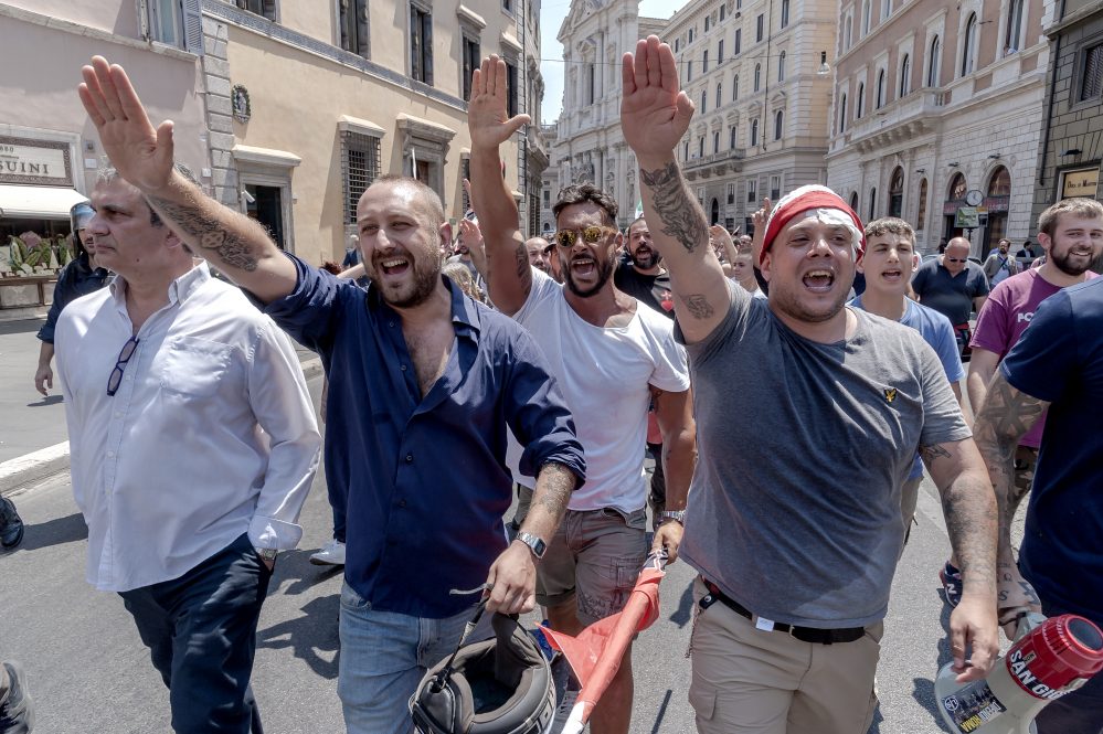 Four men giving the stiff-armed fascist salute at an anti-immigration rally in Italy.