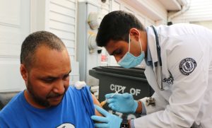 Yany Lugo of Hartford being vaccinated at his home for COVID-19 by first-year UConn medical student Amar Kalaria.