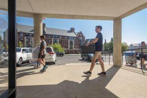 Students carry belongings into a residence hall.