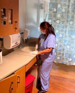 Housekeeper cleaning sink in patient room